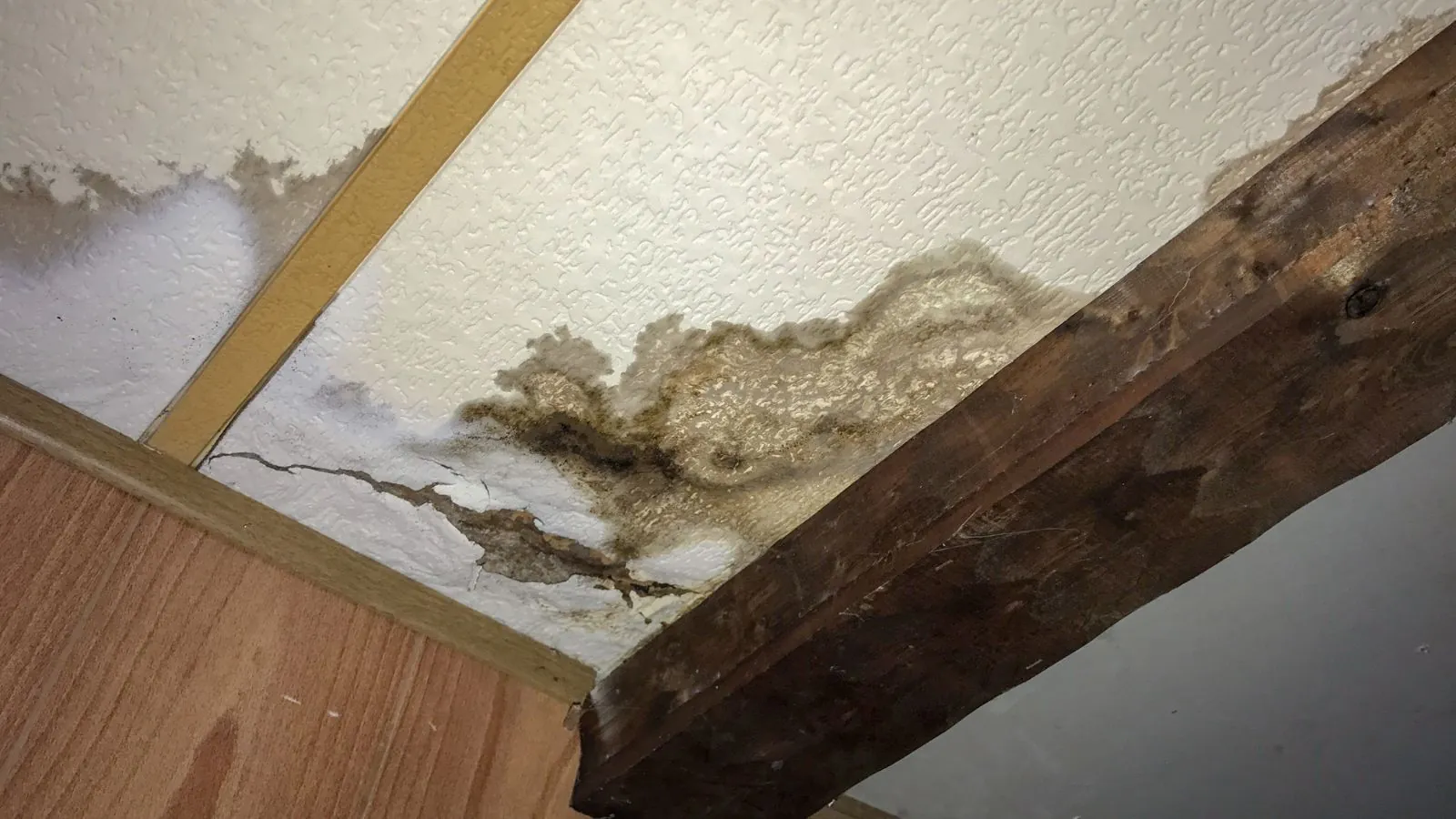 Water-stained ceiling and wooden beam showing moisture damage