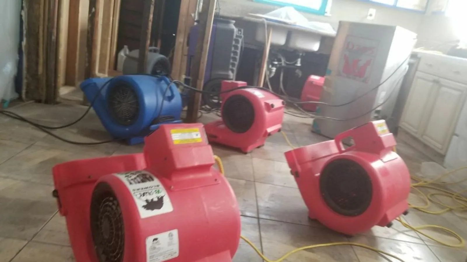 Red air movers placed around a room to dry floors and walls after a leak